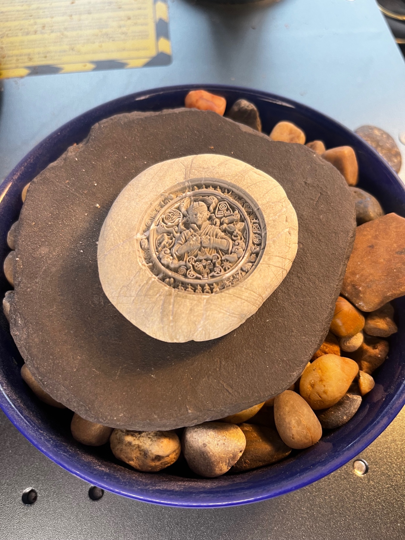 Circular sacred geometry engraving on a light natural stone resting in pebbles