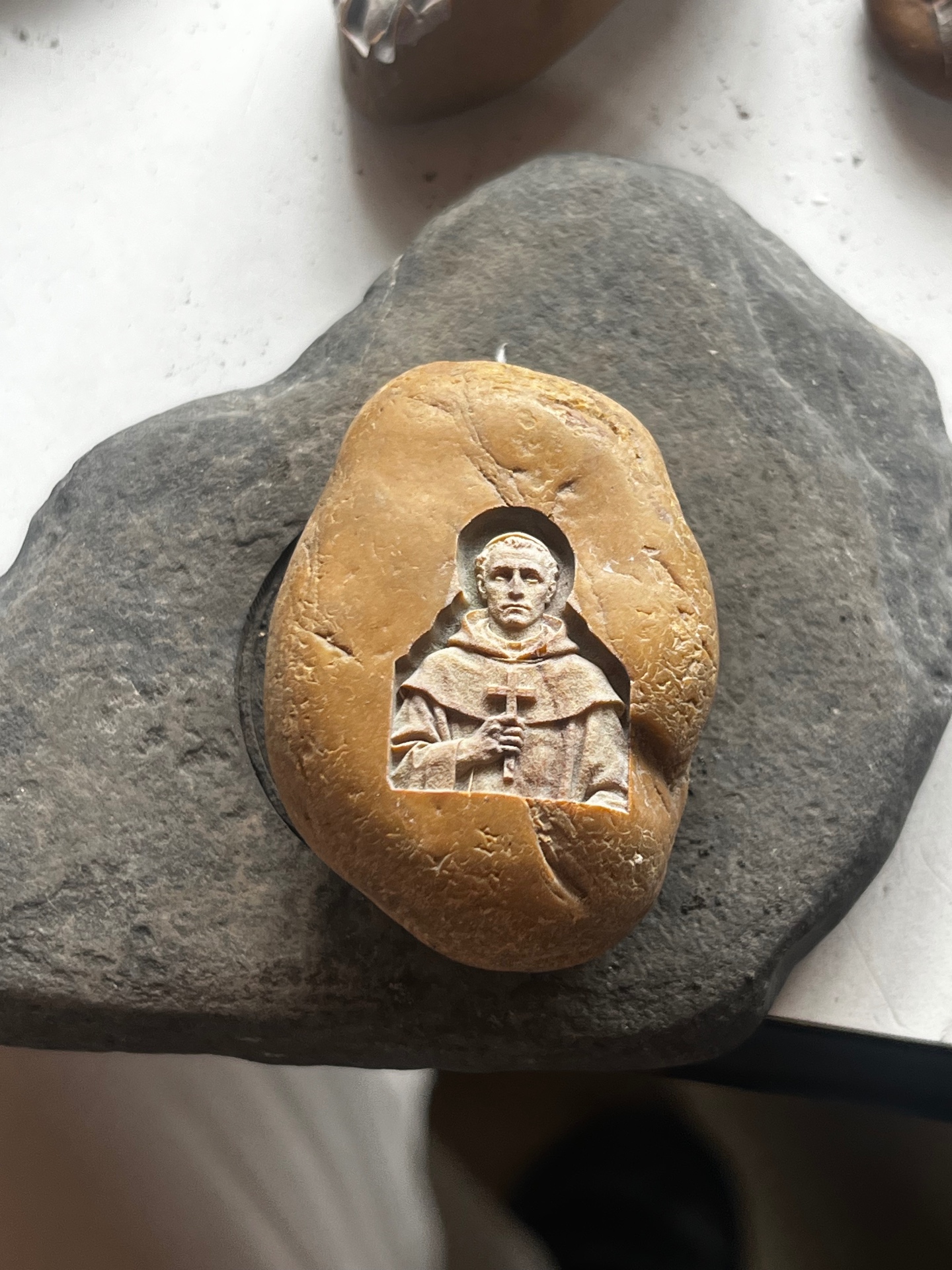 Close-up of a monk engraved in fine detail on a tan natural stone